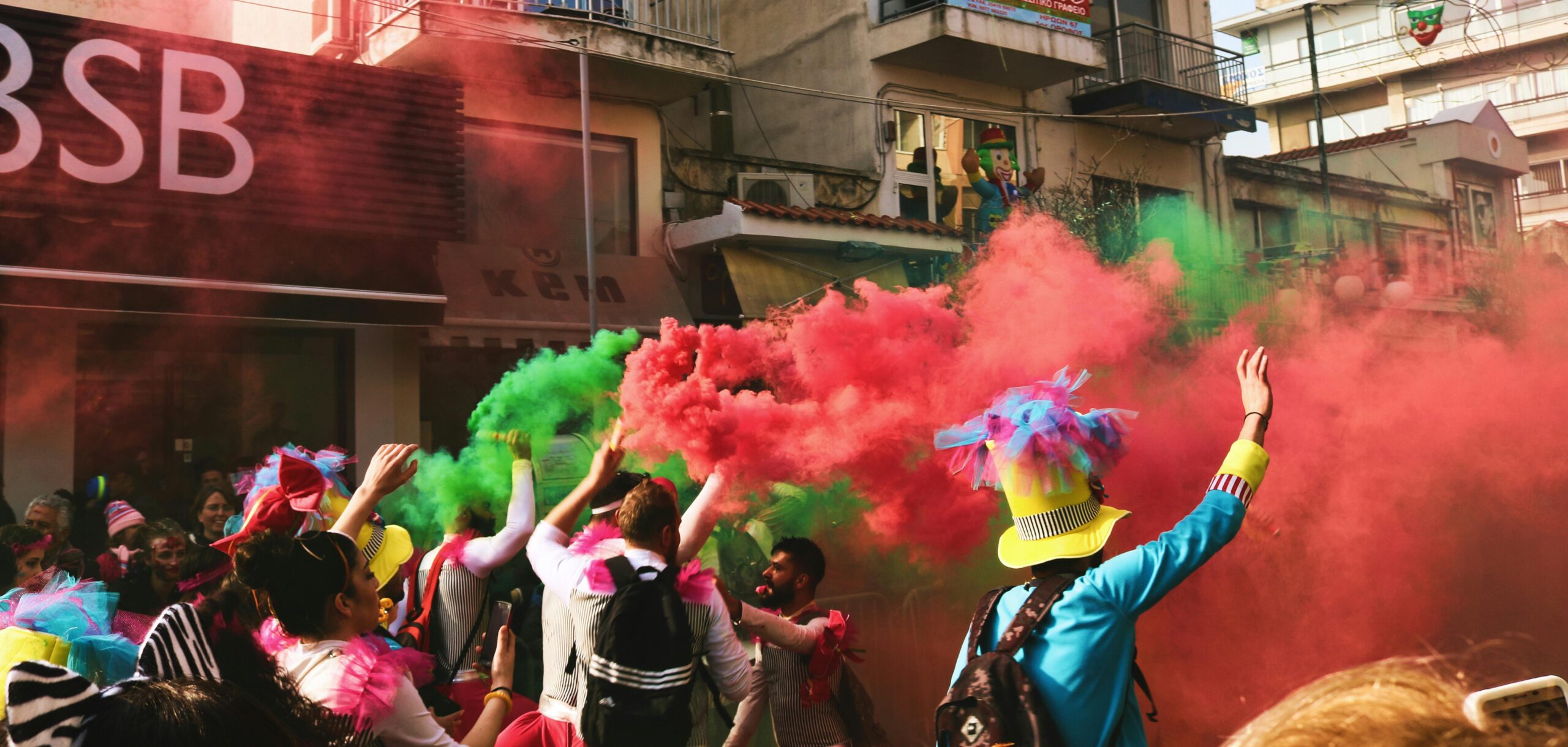 Vibrant street festival in Xanthi, Greece with colorful smoke and lively crowd.
